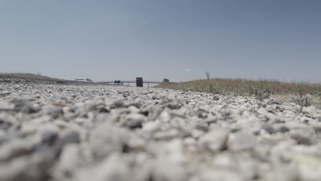 low angle view of cars driving on the highway, ground level, clear sky, agricultural bridge in the background- raw file d-log