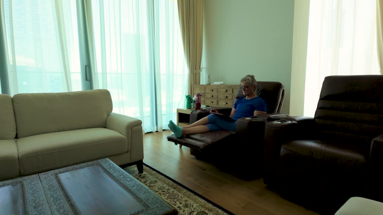 Senior woman reading from a tablet device in her downtown, city, apartment