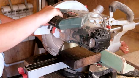 worker sawing a wood board with a circular saw. close-up hands.