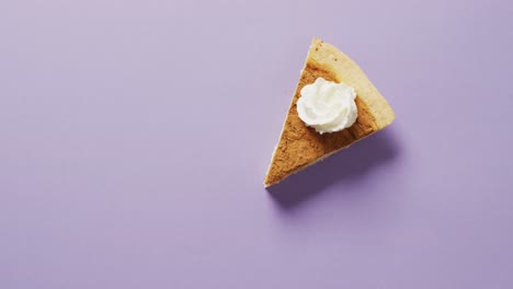 Video-of-piece-of-pumpkin-pie-with-whipped-cream-on-purple-background