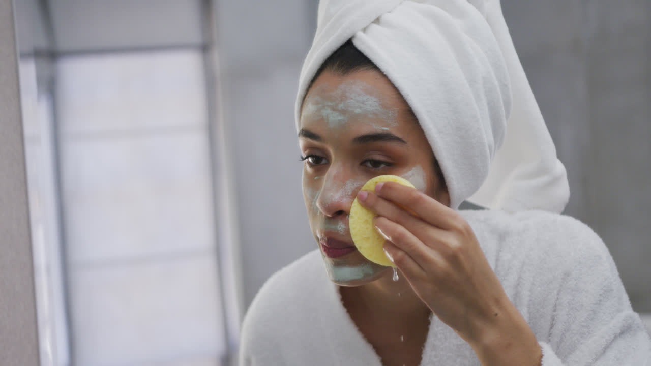 mujer de raza mixta quitando la máscara facial en el baño