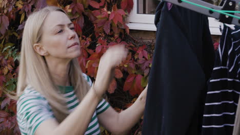 woman hanging laundry on clothes line in autumn