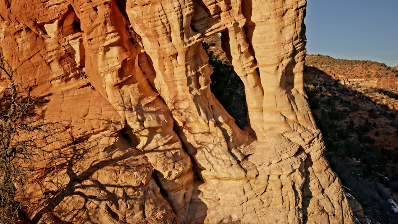 Golden-hour drone view of a breathtaking natural arch set in Utah’s rugged red rock terrain.