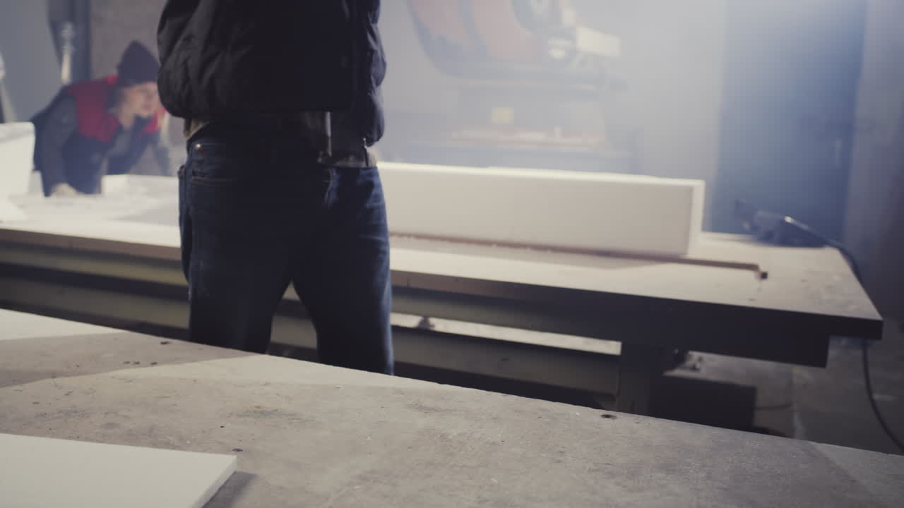 Worker measuring and handling insulation blocks in a workshop