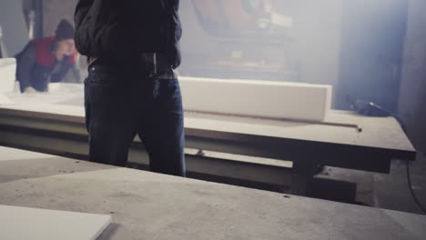 worker measuring and handling insulation blocks in a workshop