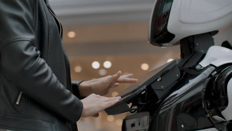 una programadora prueba el robot para la capacidad de interactuar con los usuarios. el uso de un asistente robot en la oficina. el robot da ayuda a la chica