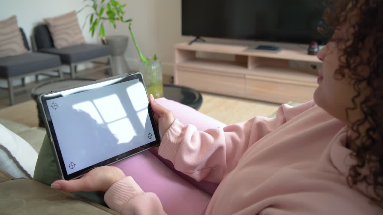 O brilho da tela está fazendo com que a pessoa incline e reposicione o tablet no sofá para uma melhor visualização