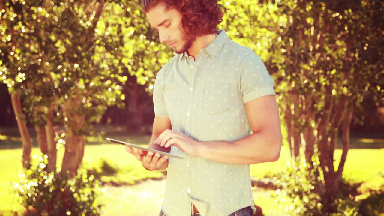 In high quality 4k format young man using tablet in the park