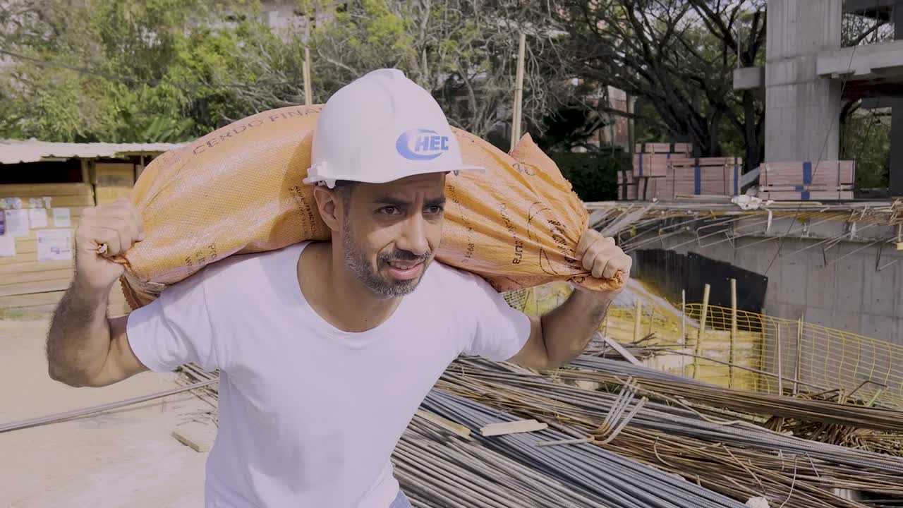 trabajador de la construcción que lleva un saco pesado en el sitio de construcción