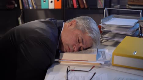 그는 임원 책상에서 잠들어 있습니다.