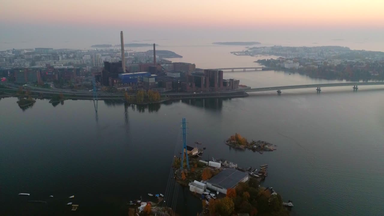 Aerial, drone shot, over the sea, of lapinlahti bridge, lauttasaari and ruoholahti, on a sunny and misty, autumn evening, in Helsinki, Finland