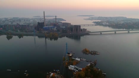 aerial, drone shot, over the sea, of lapinlahti bridge, lauttasaari and ruoholahti, on a sunny and misty, autumn evening, in helsinki, finland