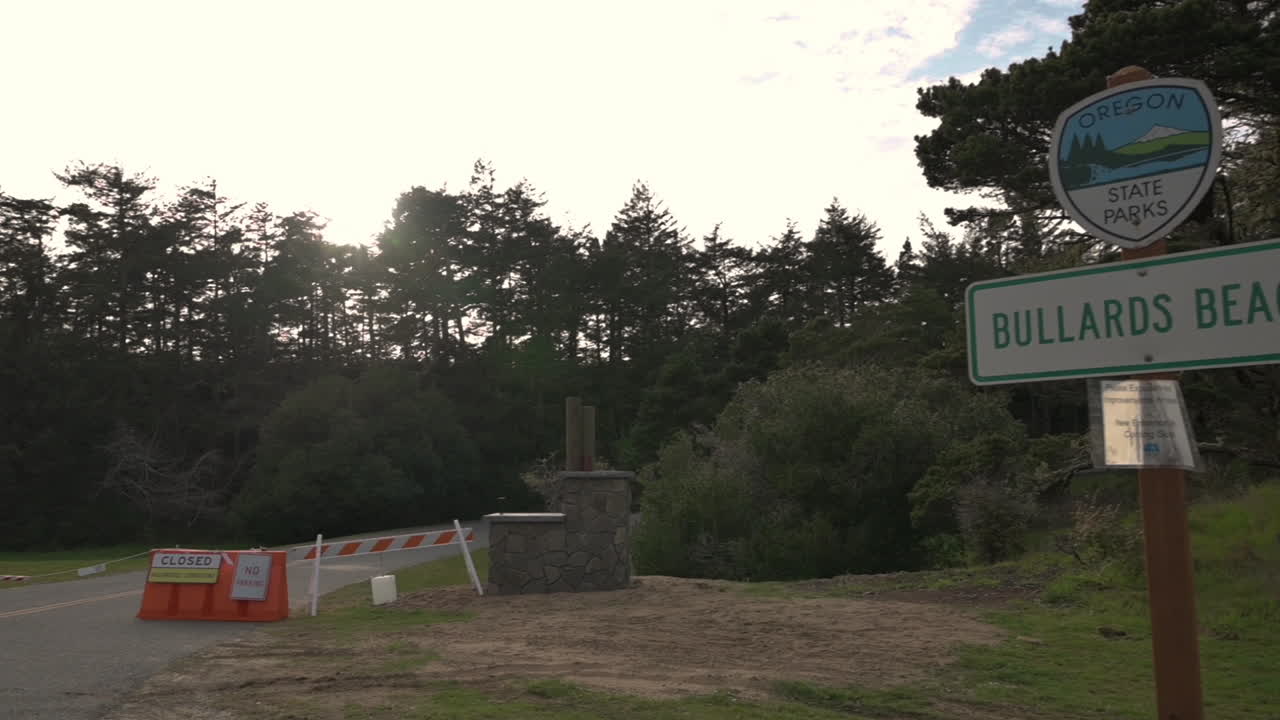 코로나바이러스 발병으로 인해 폐쇄된 오레곤주 밴던의 불라즈 비치 주립공원으로 가는 거리의 장벽과 표지판 - 패닝 샷
