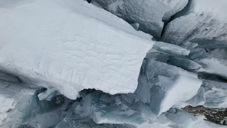 aerial close up view of the crevasses on the face of a large glacier on a sunny day in winter in the alps