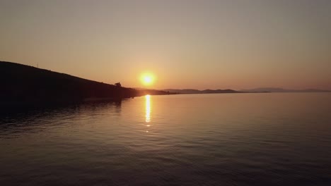 Aerial-sunset-scene-of-sea-and-town-on-shoreline-Greece