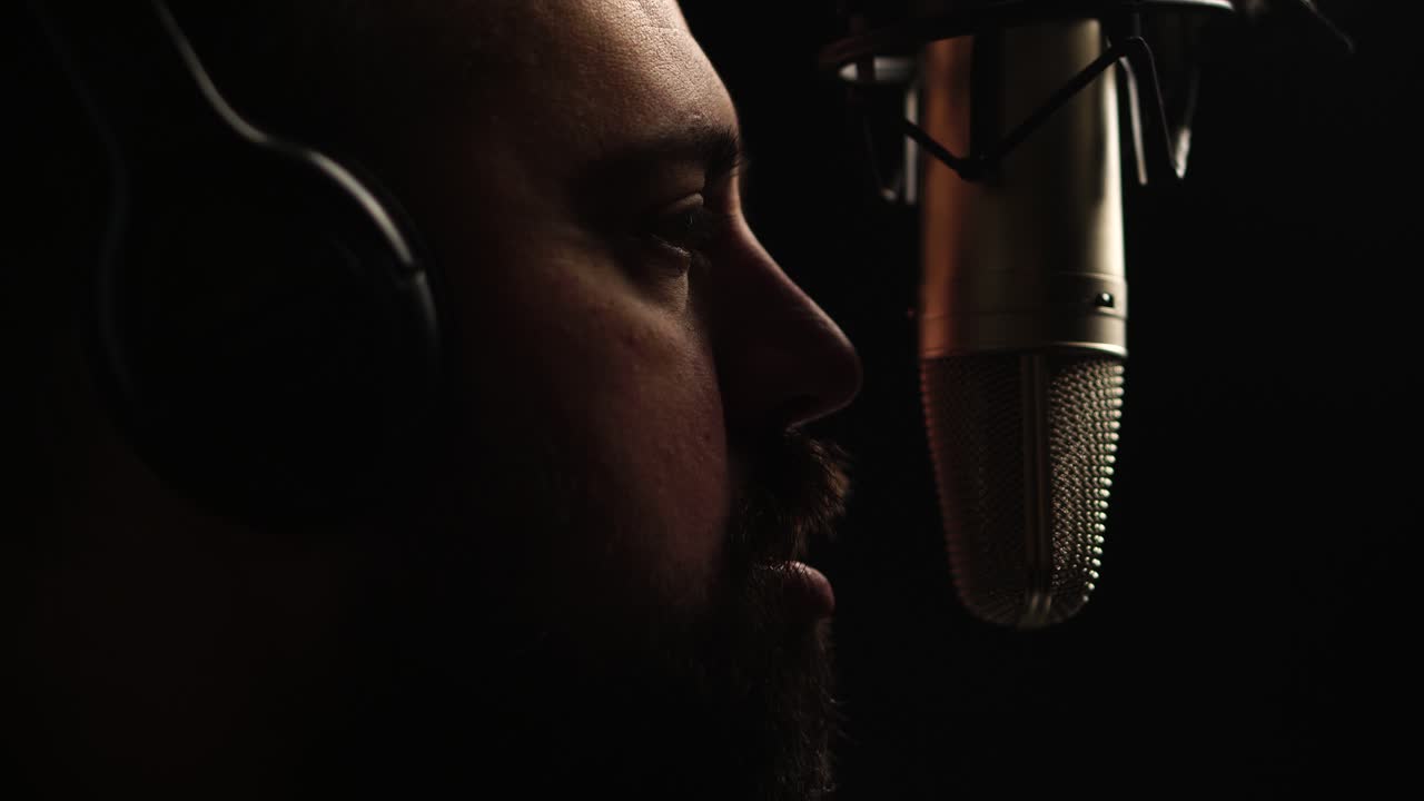 Man Talking in Front of Professional Studio Microphone in Dark Studio, Close Up
