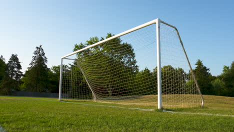 low angle shot of a soccer net and field on a sunny, summer morning