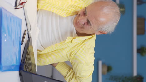 vertical video of home office worker old man has lower back pain.
