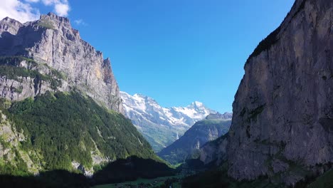 towering mountain walls and steep rock face cliffs surrounding alpine swiss valley village of lauterbrunnen, switzerland