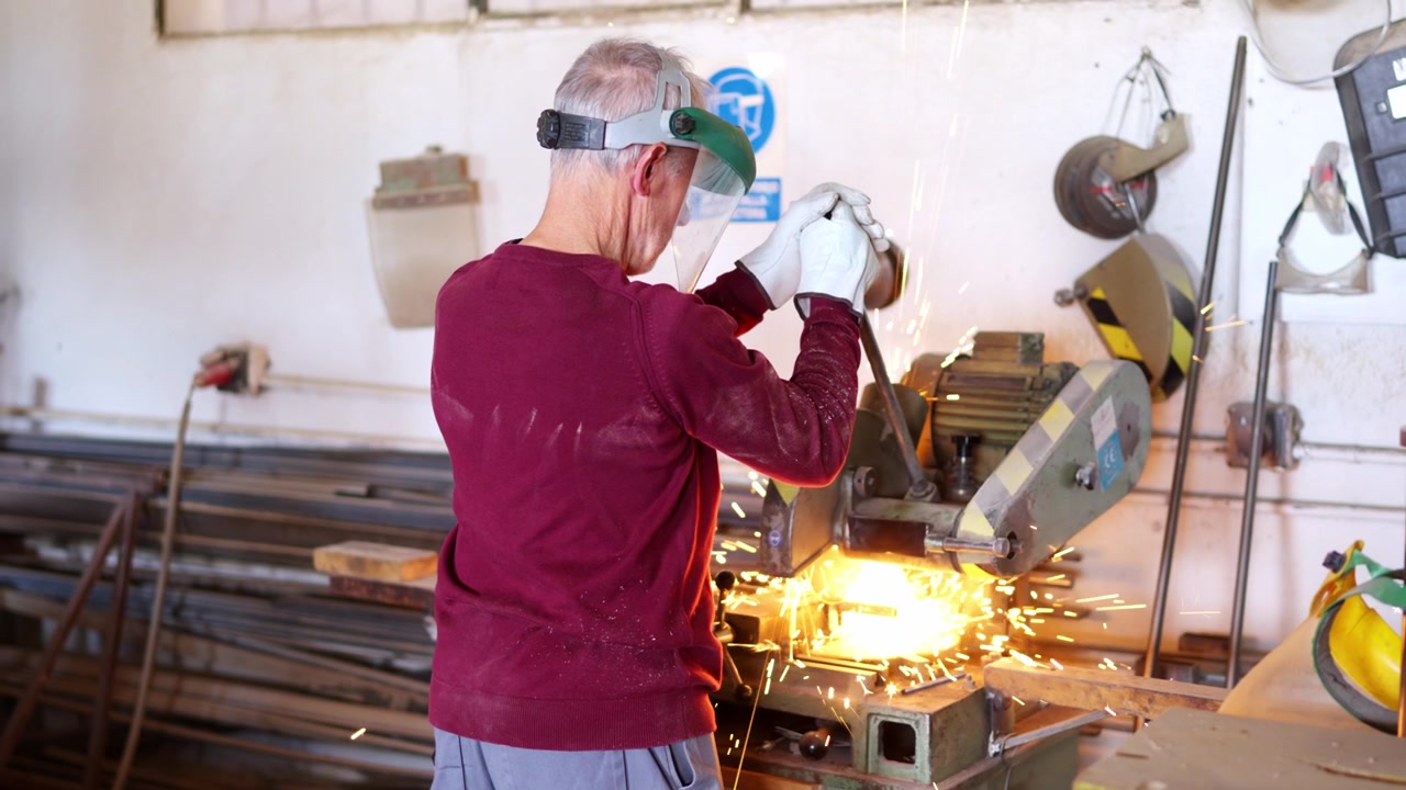 Trabajador del metal usando una sierra tronzadora para cortar tubería de acero