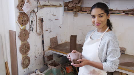 portrait of young african american woman potter holding lump of clay in ceramics studio