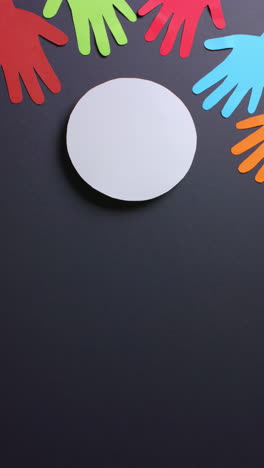 vertical video of hands around circle made of colourful paper on gray background with copy space
