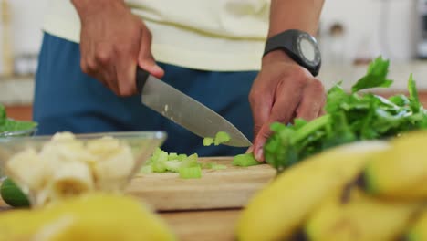 fit african american man cooking, preparing healthy green smoothie