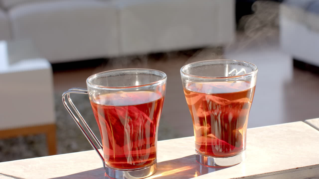 Steaming cups of tea on table in cozy living room setting, copy space