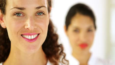 mujer de negocios sonriente con un colega detrás de ella