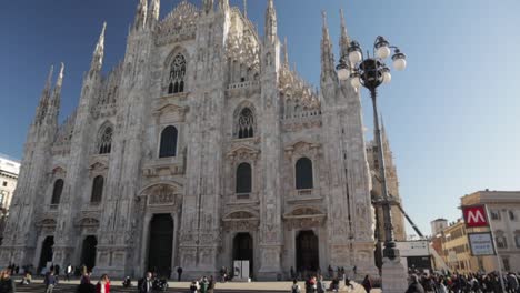 duomo di milano front facade of the famous cathedral in milan italy, arc wide slowmo shot during bright sunny day with people