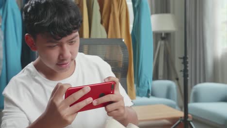 close up of asian man online seller taking photos with mobile phone while using computer for selling clothes at home