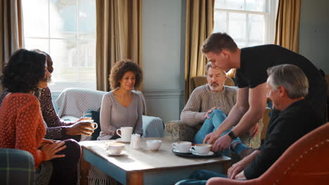 waiter serving group of mature friends in coffee shop