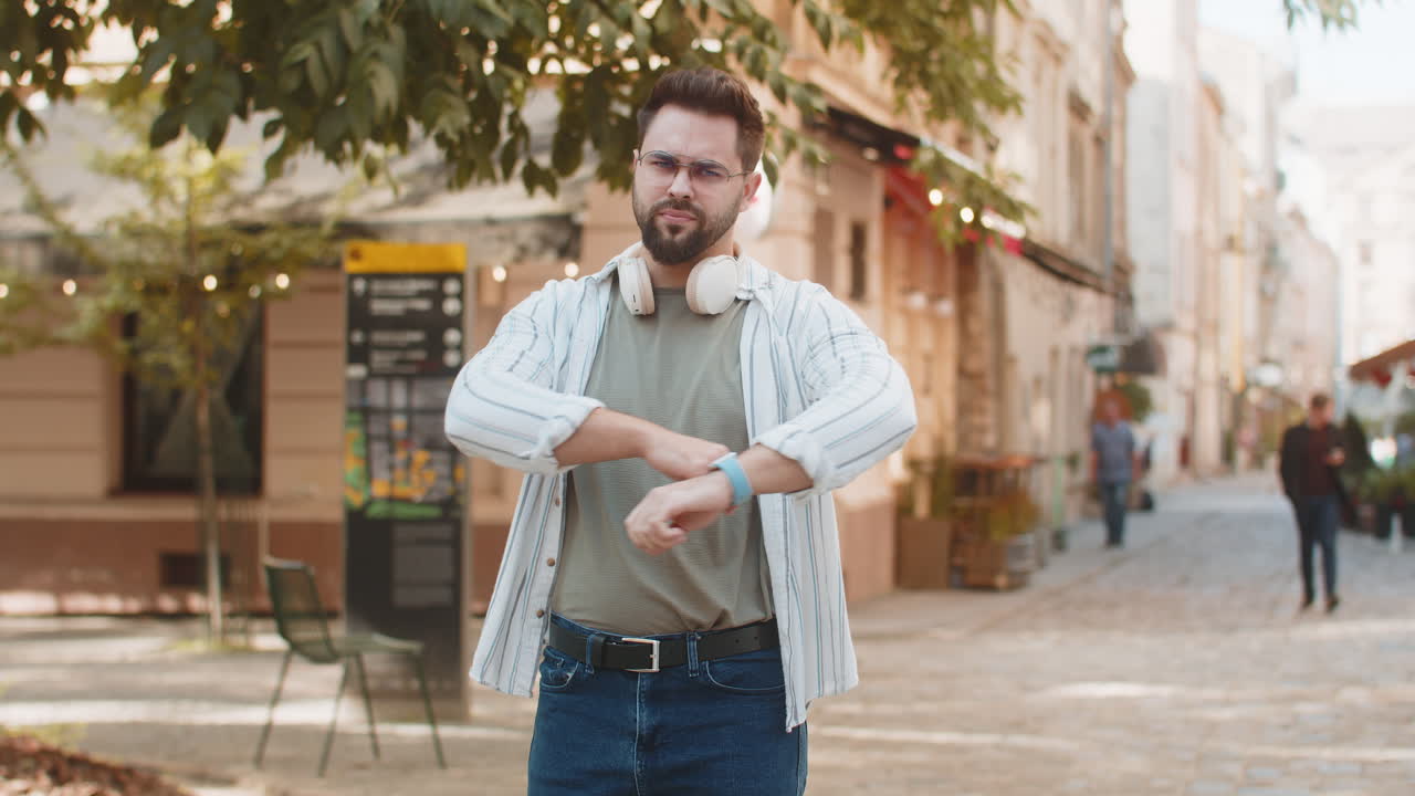 Upset young caucasian man tourist showing double thumbs down expressing discontent on city street