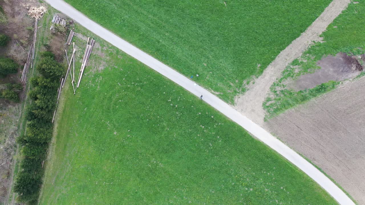 두 개의 푸른 초원 사이에 있는 거리를 따라 걷는 두 사람