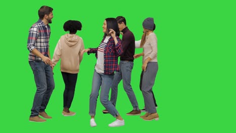 group of happy young people dancing together on a green screen, chroma key