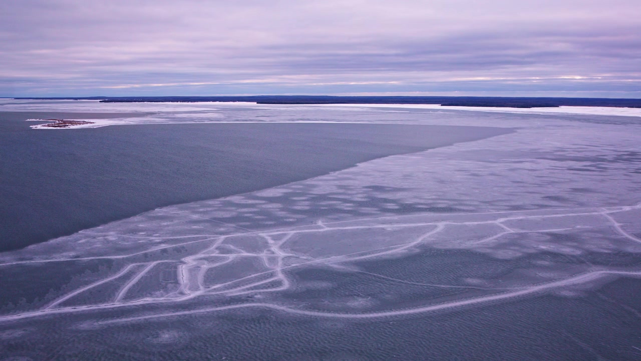 Drone footage flying over frozen lake ice in the Great Lakes region