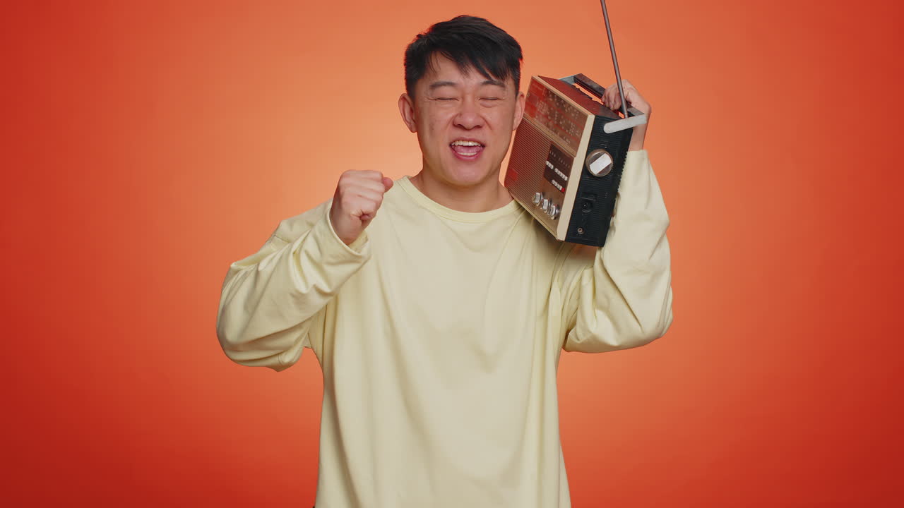 Asian man using retro tape record player to listen music disco dancing of favorite track having fun