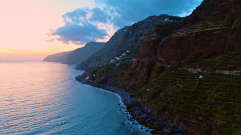 banana gardens on the slope of the steep mountain. flight along the rocky shore of the madeira islands, portugal. sunset above the atlantic ocean.