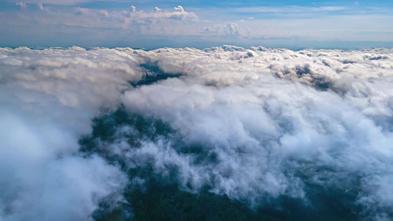 A view just above the rolling white cloud cover over a green landscape