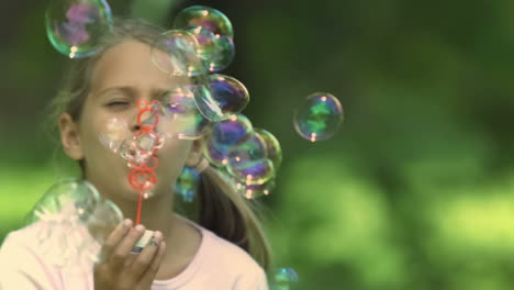 una niña en cámara lenta soplando burbujas