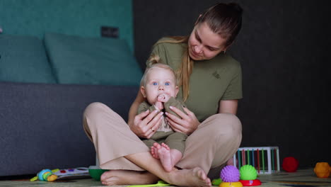 mother sits on the floor with her cute baby. mom plays with her child clapping hands.