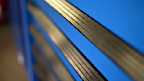 abstract clip of mechanics bright blue and black garage shop toolbox, with focus on closed door handles with black rubber grip