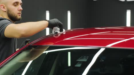 trabajador de servicio de automóviles aplicando nano recubrimiento en un detalle de automóvil.