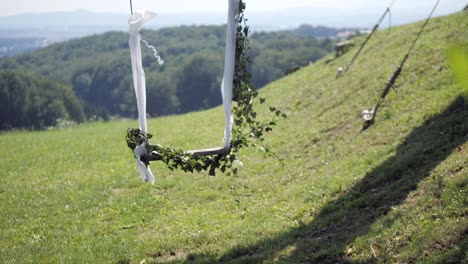 wedding decoration swing hanging from tree decorated with ivy, sunny summer day