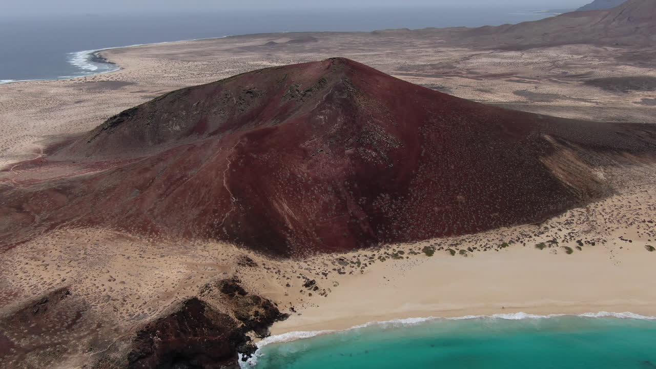 playa de las conchas, isla de la graciosa: vista aérea en órbita de la montaña bermeja en la playa de las conchas en un día soleado y aguas turquesas