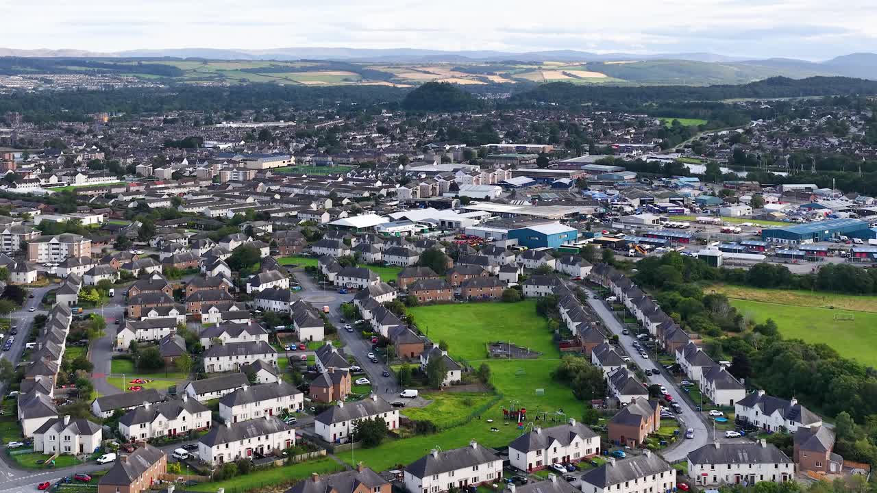Drone glides above Dundee’s residential area, revealing rooftops, green spaces, and distant hills