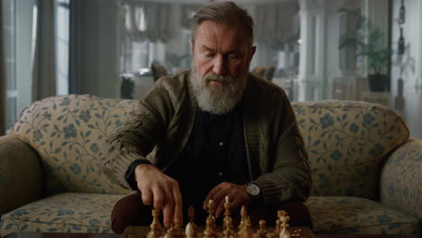 senior man playing chess alone in classic living room