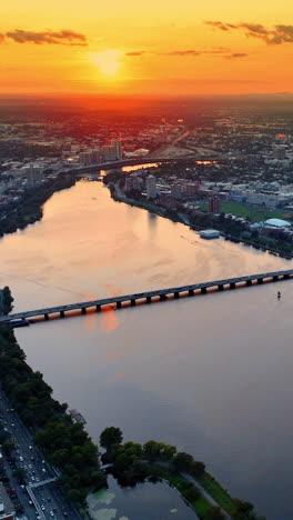splendid view of the charles river and scenery of boston after sunset. multiple yacht are on the water. orange sky above the city.. vertical video