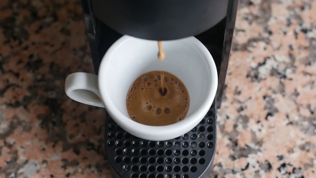 Slow motion of a working coffee machine filling a cup.