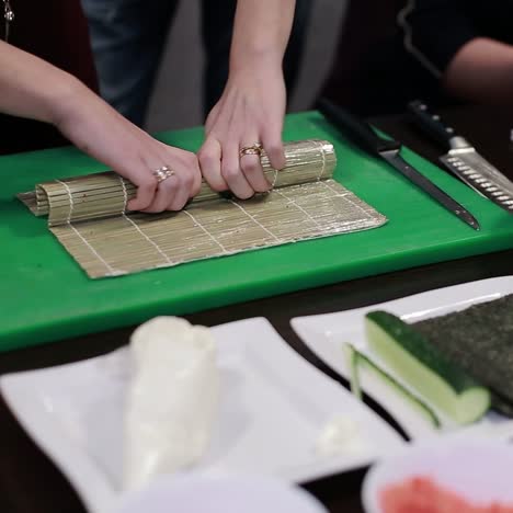 closeup of chef hands rolling up sushi